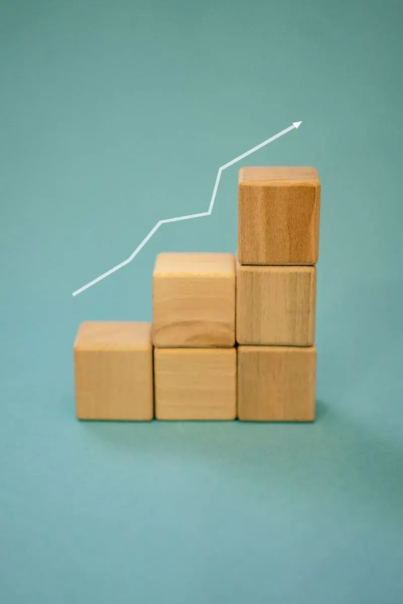 Wooden blocks forming a staircase with an upward arrow symbolizing growth and progress.